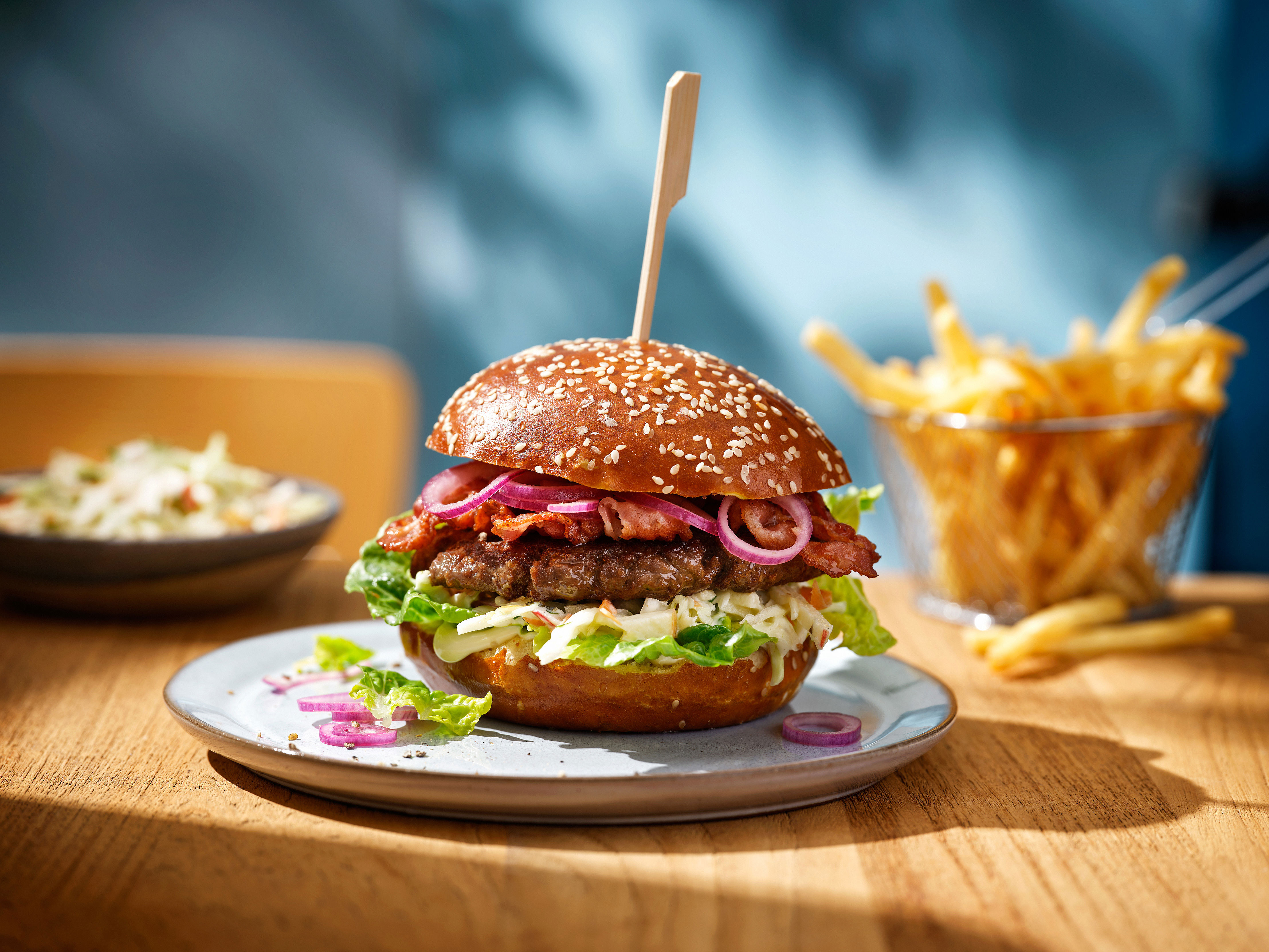 Pretzel sesam hamburger bun met beefburger, spek en rode ui